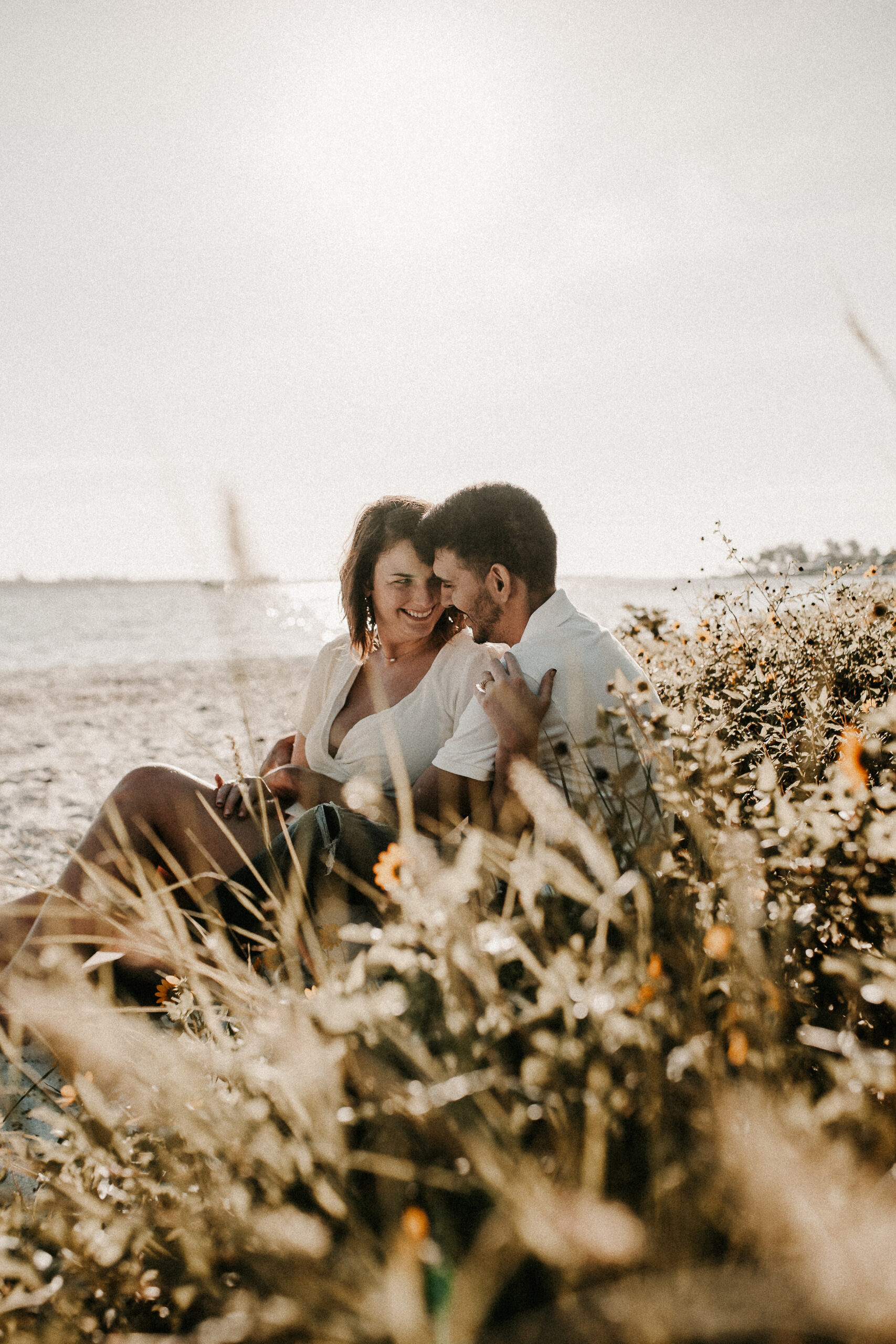 Couple cuddled on the beach in the flowers after their elopement in Bradenton Florida