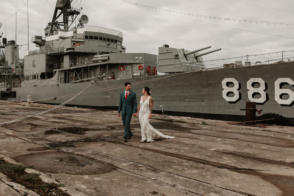 Jennah and Ross walking in front of the USS Orleck during their destination elopement in Florida