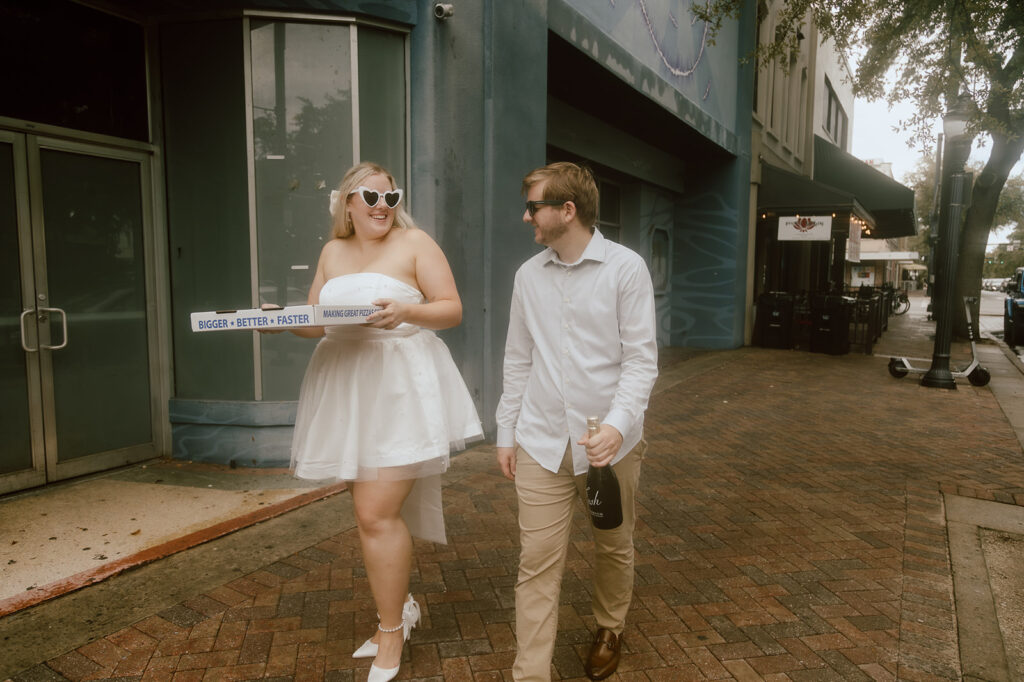 Couples walking down the street carrying champagne and pizza during their elope in Florida