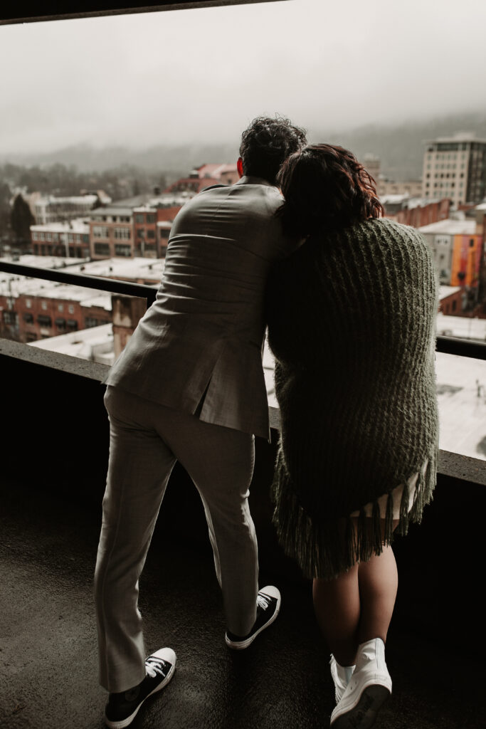 Danielle and Jon looking at the mountains on a rainy day in Asheville in a parking garage