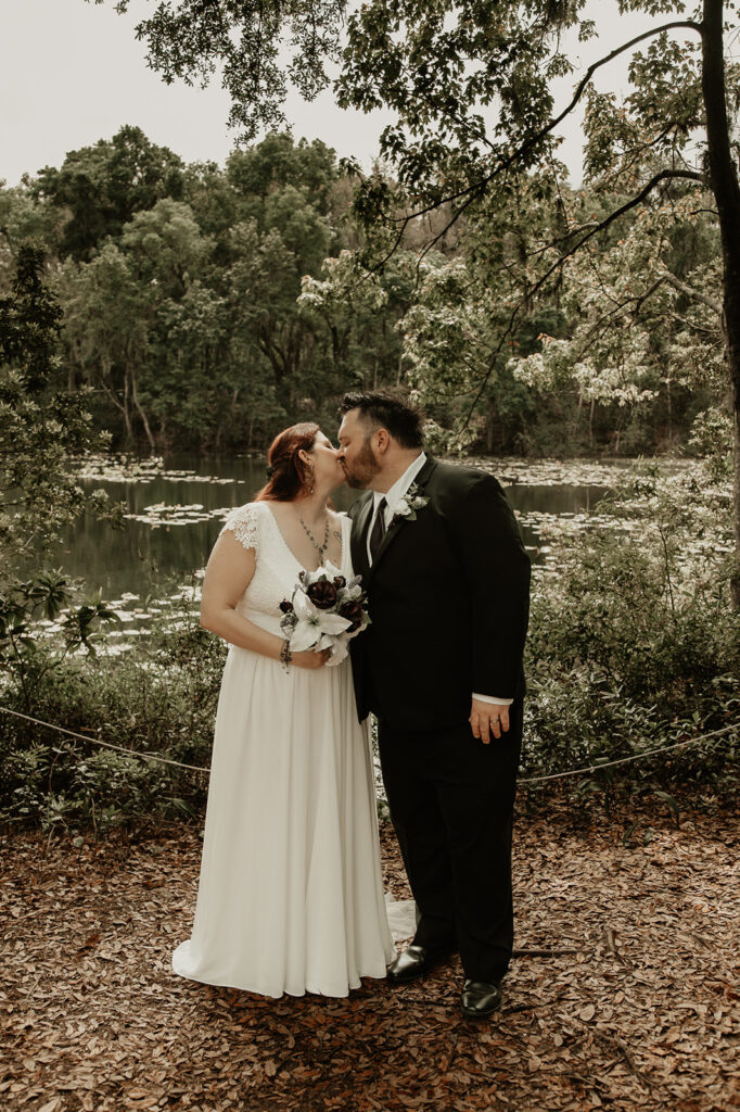 bride and groom kissing near the lake at their botanical garden elopement in florida