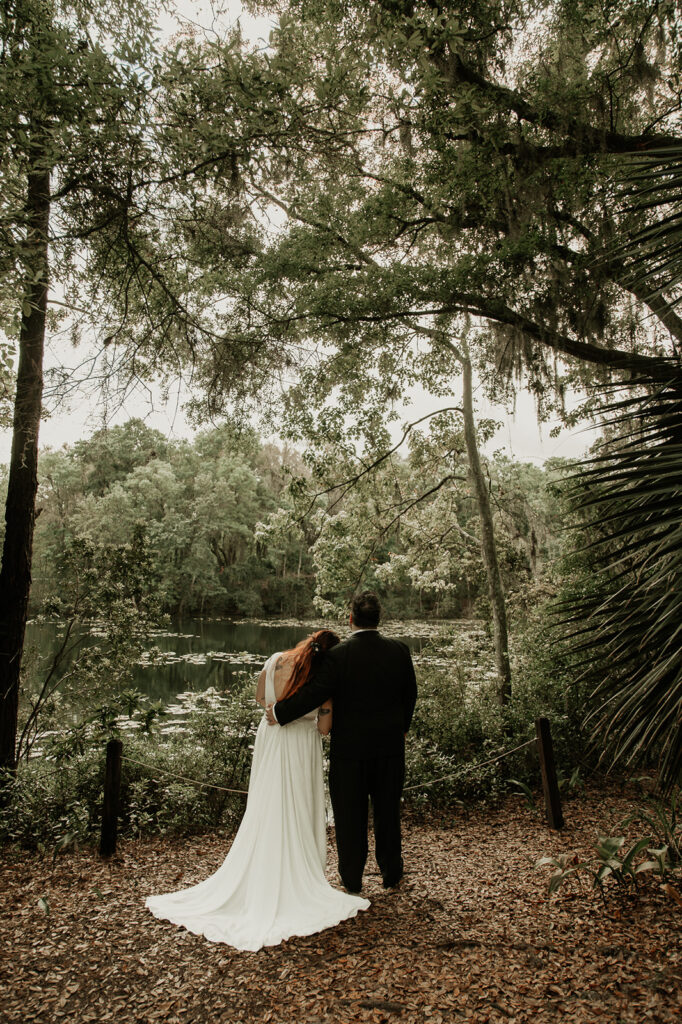 bride resting her head on the grooms shoulder looking out at the lake