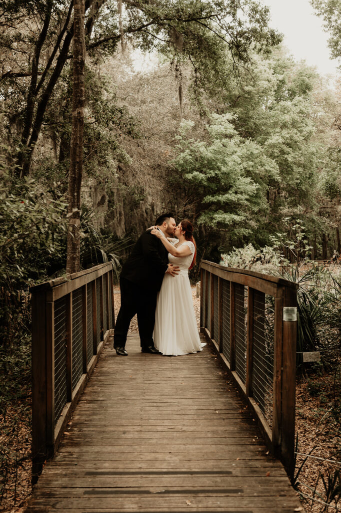 bride and groom kissing on a bridge in the gardens during their fall elopement in Florida