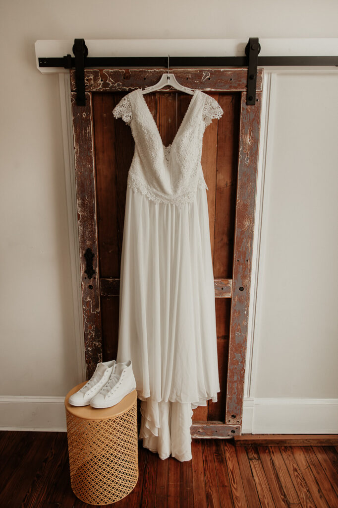 lace white wedding dress hanging from barn door 