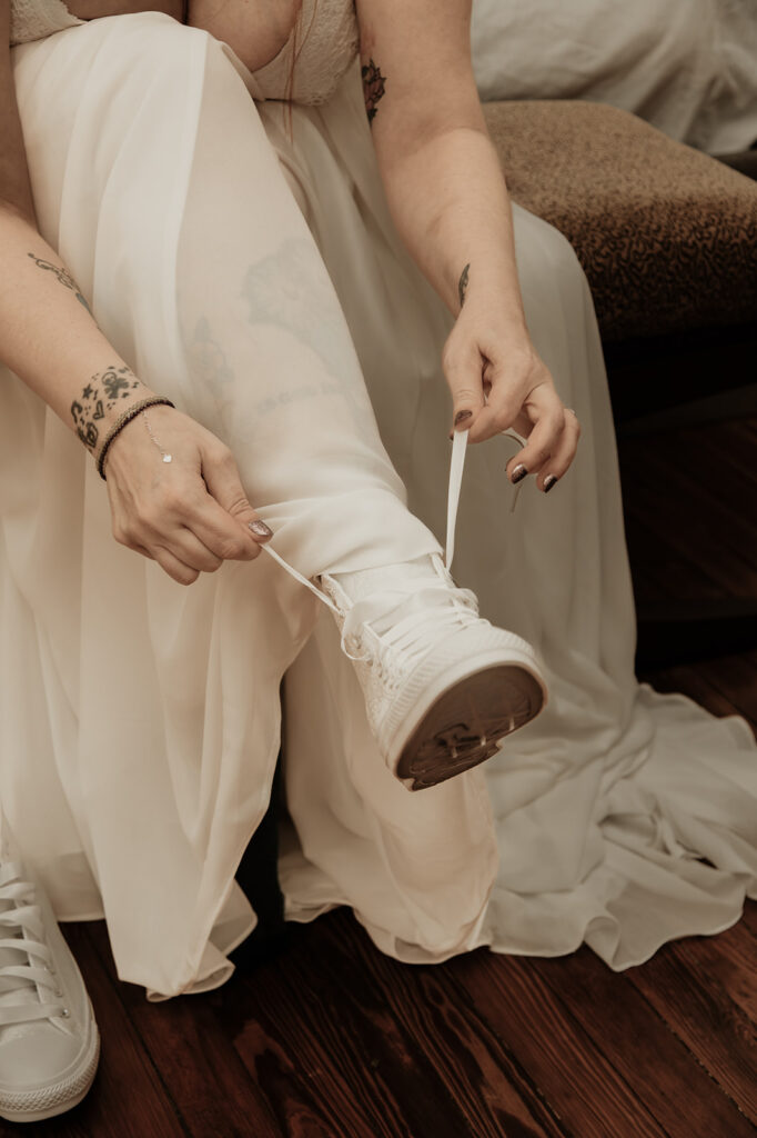 bride lacing up her wedding day converse for her botanical garden elopement in florida