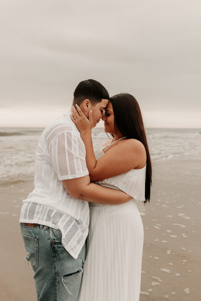 Brides foreheads together at the beach after ceremony