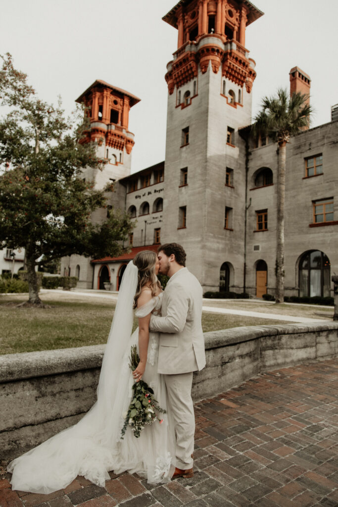 Bride and groom are kissing on the cobble stone side walk of st augustine