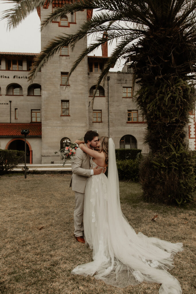 Bride and groom are kissing in front of the lightern museum in st Augustine Florida