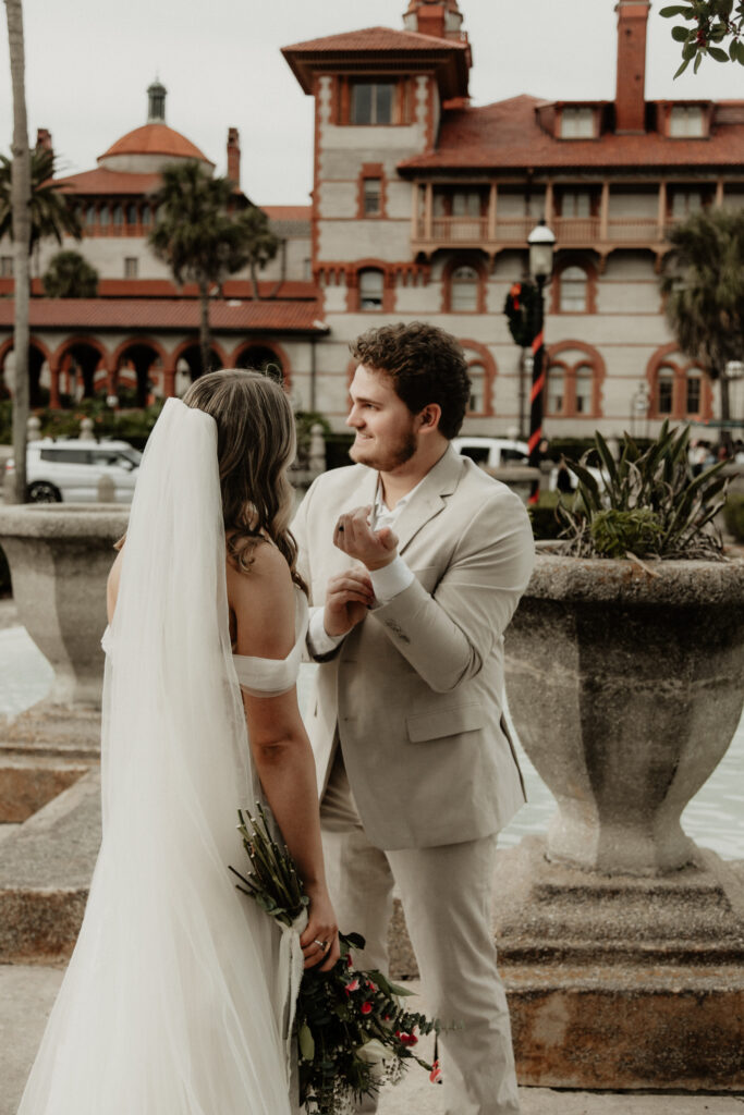 groom is fixing his jacket sleeve. bride is staring at him with love