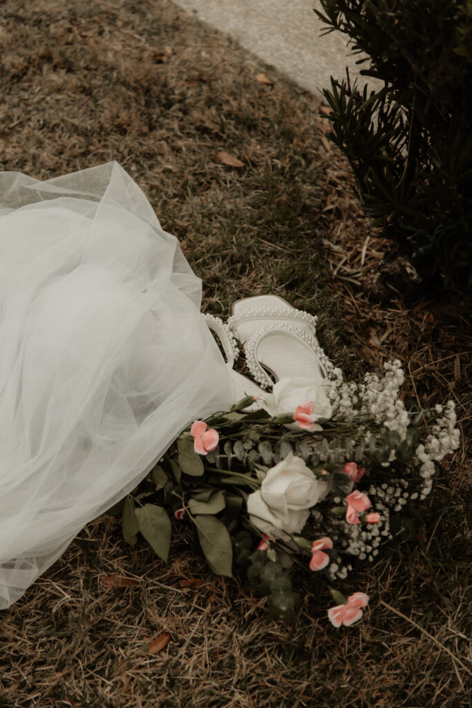 brides shoes, veil and flowers laying on the ground