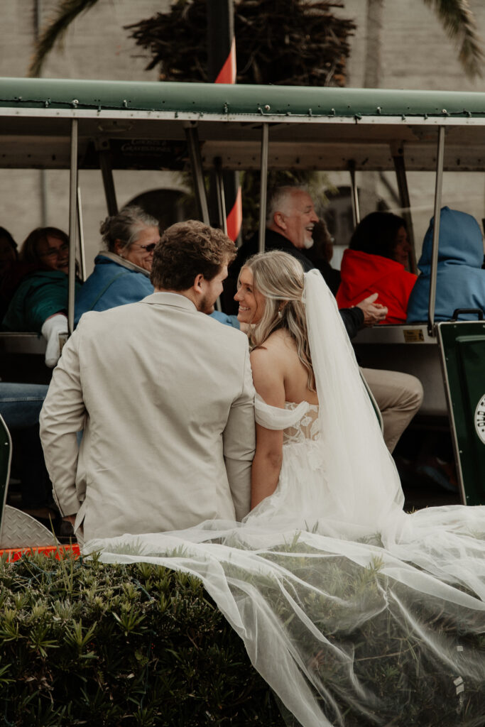 bride and groom are leading up against the bushes looking at each other. The st augustine trolly full of people pulled up and they all cheered the newly weds