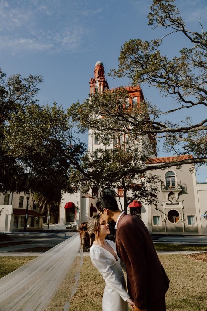 Groom kissing bride on the forehead in front of the Treasury in St Augustine